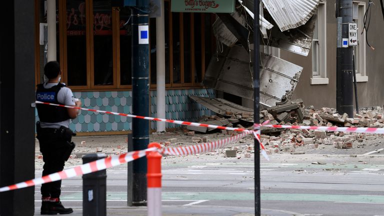 A police officer closes an intersection where debris is scattered in the road after an earthquake damaged a building in Melbourne, Wednesday, Sept. 22, 2021. A magnitude 5.8 earthquake caused damage in the city of Melbourne in an unusually powerful temblor for Australia, Geoscience Australia said. (James Ross/AAP Image via AP)