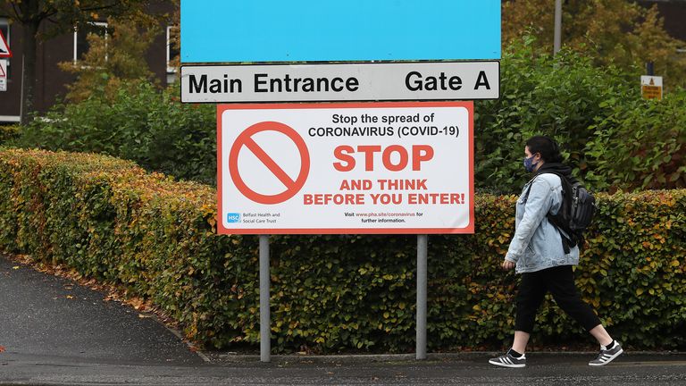 A woman wearing a face mask walks past an entrance to Belfast City Hospital