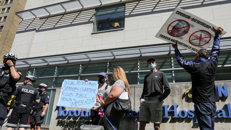 Protesters hold signs during an anti-vaccine mandate protest outside Toronto General Hospital in Toronto