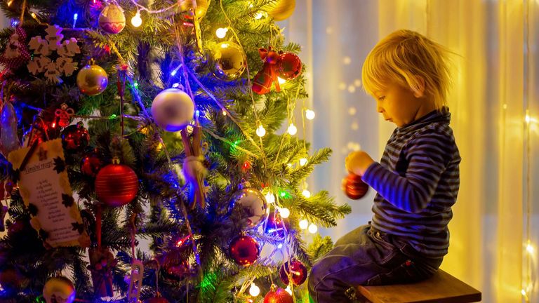   petit garçon blond, décoration d'arbre de Noël avec des boules et des guirlandes lumineuses à la maison PIC:ALAMY