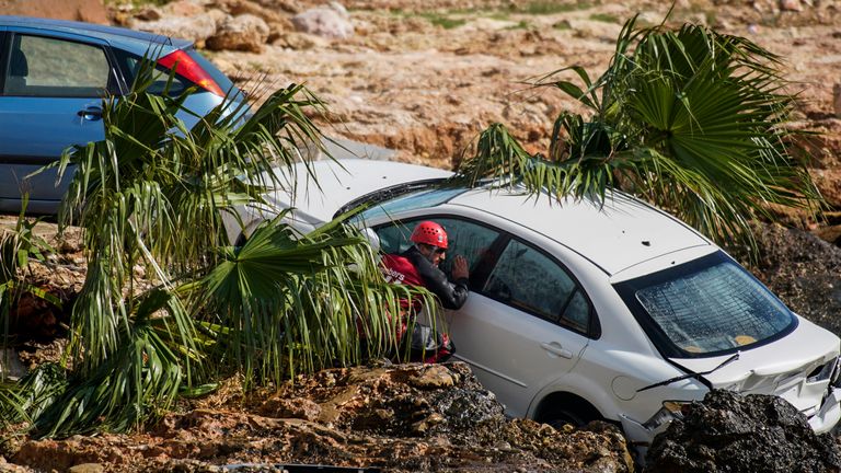 Seorang petugas pemadam kebakaran memeriksa bangkai mobil yang terjebak di pantai kota tepi laut Alcanar di timur laut Spanyol pada Kamis, 2 September 2021 PIC: AP