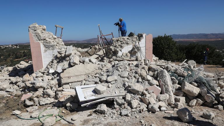 A camera operator films amid the rubble of a demolished church following an earthquake, in the town of Arkalochori on the island of Crete, Greece, September 27, 2021. REUTERS/Stefanos Rapanis