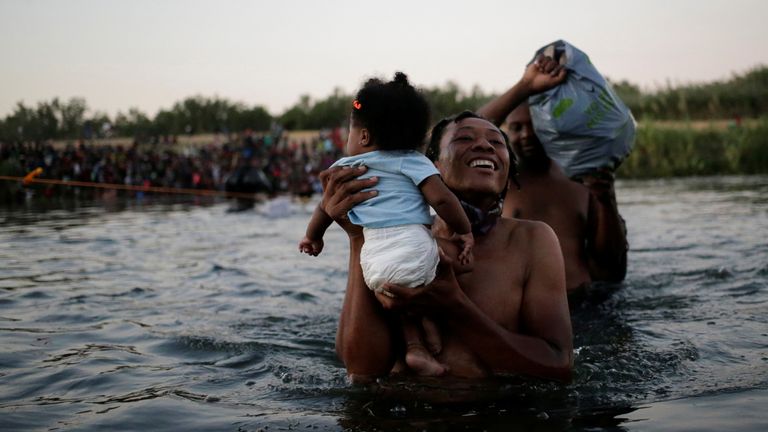 A migrant man seeking refuge in the United States walks back into the Mexican side carrying his daughter while crossing the Rio Bravo river which divides the border between Ciudad Acuna, Mexico and Del Rio, Texas, U.S., to avoid being deported, in Ciudad Acuna, Mexico, September 19, 2021. REUTERS/Daniel Becerril