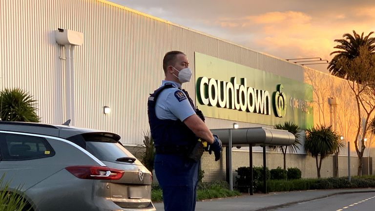  A police officer stands guard outside the New Lynn supermarket in Auckland, New Zealand