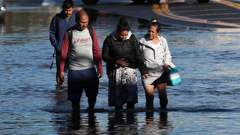 Local residents wade through floodwaters as they escape their homes after the remnants of Tropical Storm Ida brought drenching rain, flash floods and tornadoes to parts of the northeast in Mamaroneck, New York