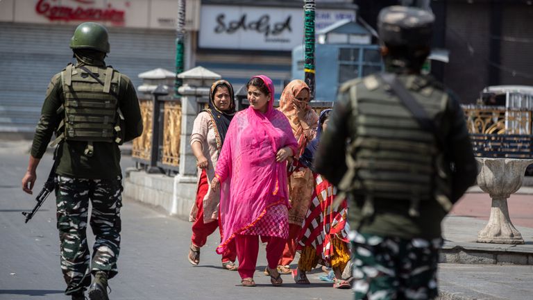 Indian paramilitary soldiers patrol as civilians walk in a deserted market area in Srinagar, Indian controlled Kashmir. Pic: AP