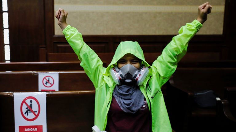 An environmental activist wearing a protective mask reacts inside the courtroom during the hearing