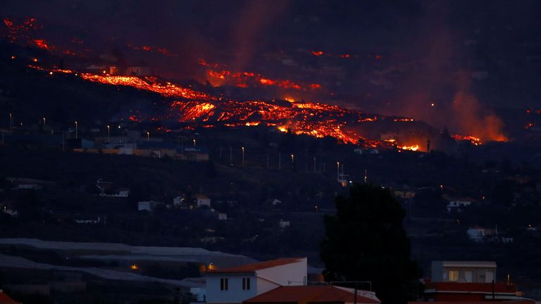 La lava fluye detrás de las casas después de una erupción volcánica en España