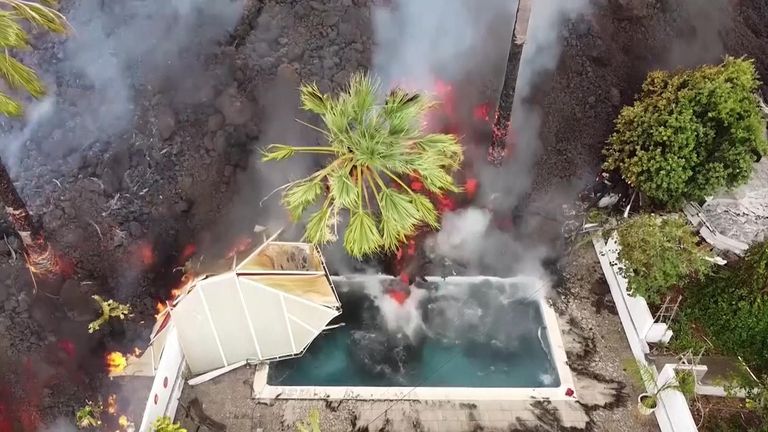 Drone view of lava swallowing swimming pool and homes on La Palma