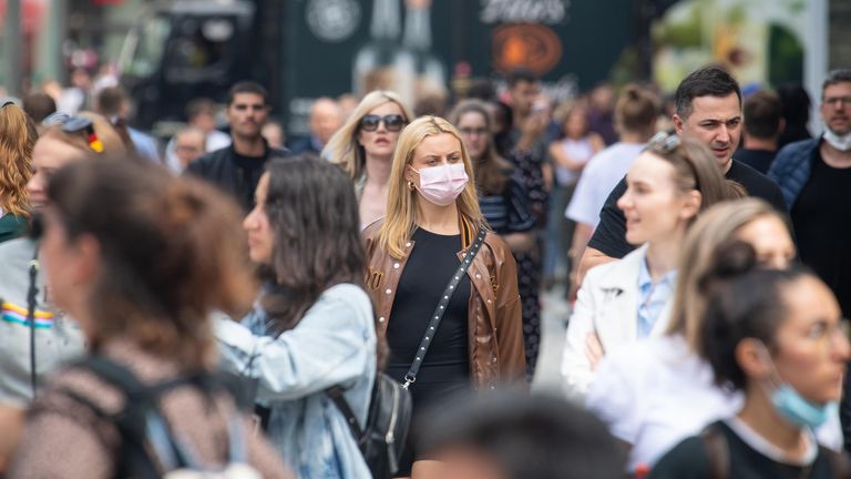 A woman wears a face mask among a crowd of pedestrians on Oxford Street, London