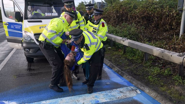 Police officers detain a protester from Insulate Britain occupying a roundabout leading from the M25 motorway to Heathrow Airport in London. 