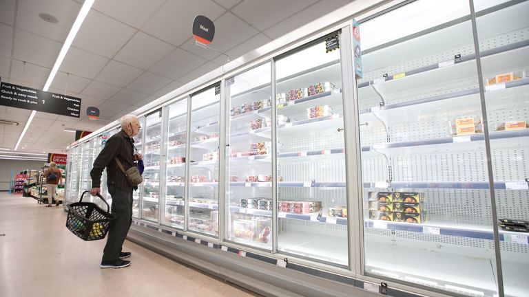 A shopper looks at produce and empty shelves of the meat aisle in Co-Op supermarket, Harpenden