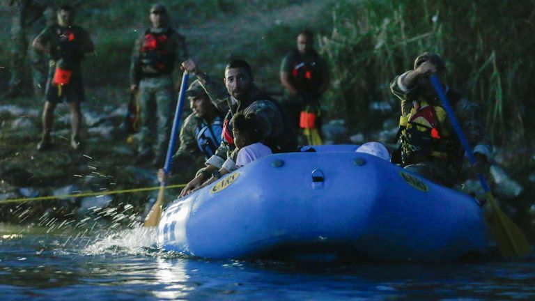 Border Patrol Agents with an inflatable boat help migrants seeking refuge to cross into the U.S., near the banks of the Rio Grande river in Del Rio, Texas