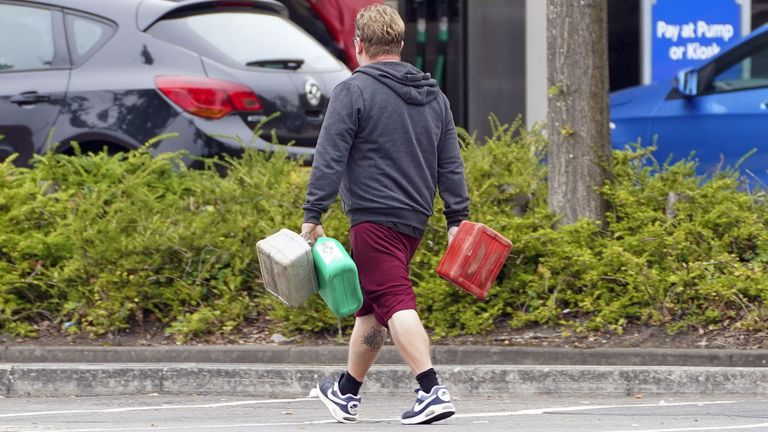 A man carrying containers at a petrol station in Bracknell, Berkshire