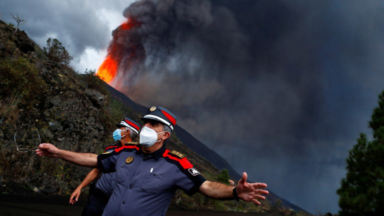 2021年9月22日、スペインのタカネにあるラパルマ島で火山が噴火した後、溶岩が上昇するにつれて警察官が道路を封鎖しました。