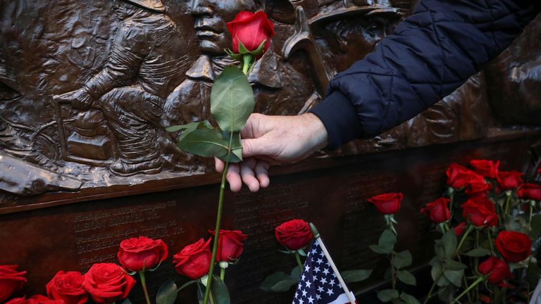 A family member of 9/11 victims adds a flower at FDNY Ten House