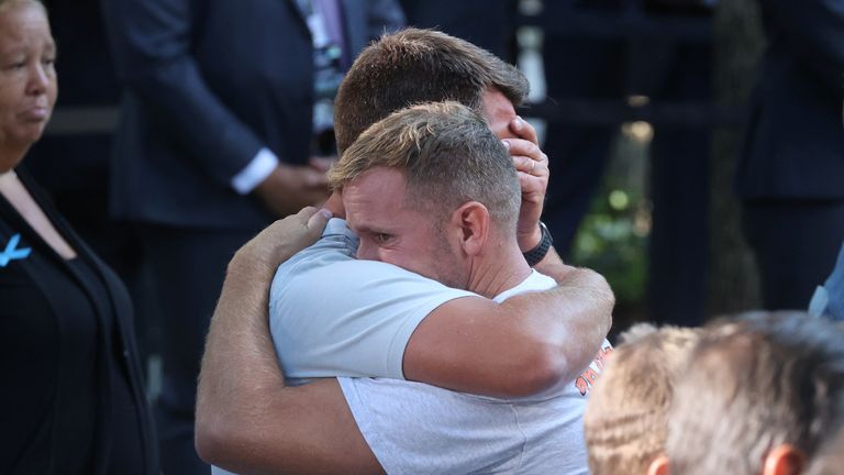Mourners hug as they participate in the ceremony