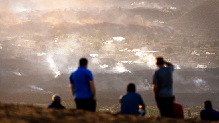 Residents look from a hill as the lava from a volcano eruption flows on the island of La Palma in the Canaries, Spain  PIC:AP