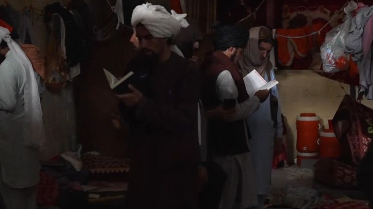 Taliban fighters flip through books and rifle through the belongings