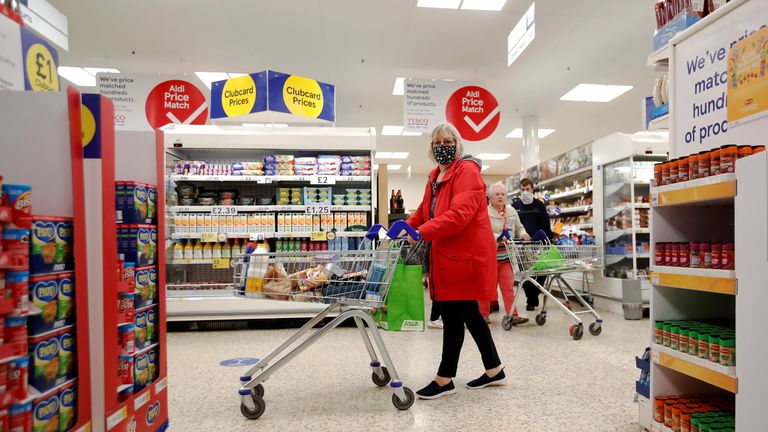 A woman wearing a face mask pushes a shopping cart at a Tesco supermarket in Hatfield, Britain October 6, 2020