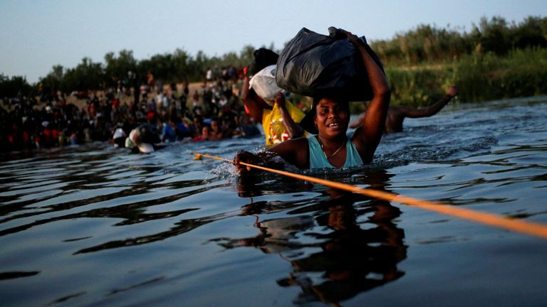 Migrants seeking refuge in the United States walk back into the Mexican side carrying their belongings inside plastic bags while crossing the Rio Bravo river which divides the border between Ciudad Acuna, Mexico and Del Rio, Texas, U.S., to avoid being deported, in Ciudad Acuna, Mexico, September 19, 2021. REUTERS/Daniel Becerril REFILE- QUALITY REPEAT