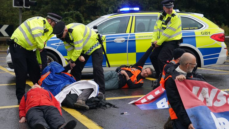 Des policiers arrêtent des manifestants d'Isulate Britain occupant un rond-point menant de l'autoroute M25 à l'aéroport d'Heathrow à Londres. 