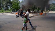 A man and a child walk by burning tires on a street in Port-au-Prince, Haiti, Sunday, Oct. 17, 2021. A group of 17 U.S. missionaries including children was kidnapped by a gang in Haiti on Saturday, Oct. 16, according to a voice message sent to various religious missions by an organization with direct knowledge of the incident.