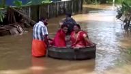A bride and groom float to a temple in a cooking vessel on a flooded road for their wedding ceremony