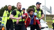 Police officers detain an Insulate Britain activist blocking a roundabout at a junction on the M25 motorway as they a protest in Thurrock, Britain October 13, 2021. REUTERS/Henry Nicholls  