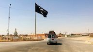 FILE - This Tuesday, July 22, 2014 file photo shows a motorist passing by a flag of the Islamic State group in central Rawah, 175 miles (281 kilometers) northwest of Baghdad, Iraq. Iraq’s Defense Ministry said Friday, Nov. 17, 2017 Iraqi forces have retaken the last IS-held town in the country, more than three years after the militant group stormed nearly a third of Iraqi territory.(AP Photo, File)