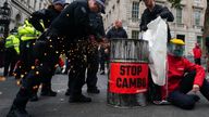 Police officers cutting an oil barrel as campaigners from Greenpeace protest outside Downing Street, London, against the Cambo oil field off the west coast of Shetland. Picture date: Monday October 11, 2021.