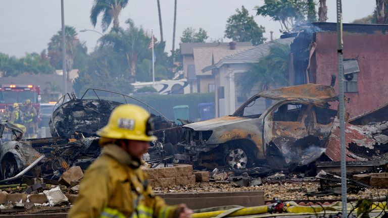 Fire crews work the scene of a small plane crash, Monday, Oct. 11, 2021, in Santee, Calif. At least two people were killed and two others were injured when the plane crashed into a suburban Southern California neighborhood, setting two homes ablaze, authorities said. (AP Photo/Gregory Bull)
