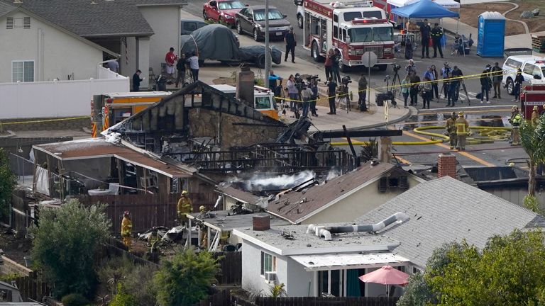 Emergency crews work a the scene of a small plane crash, Monday, Oct. 11, 2021, in Santee, Calif. Authorities say at least two people were killed and two others were injured when the plane crashed into a suburban Southern California neighborhood, setting two homes ablaze. (AP Photo/Gregory Bull)