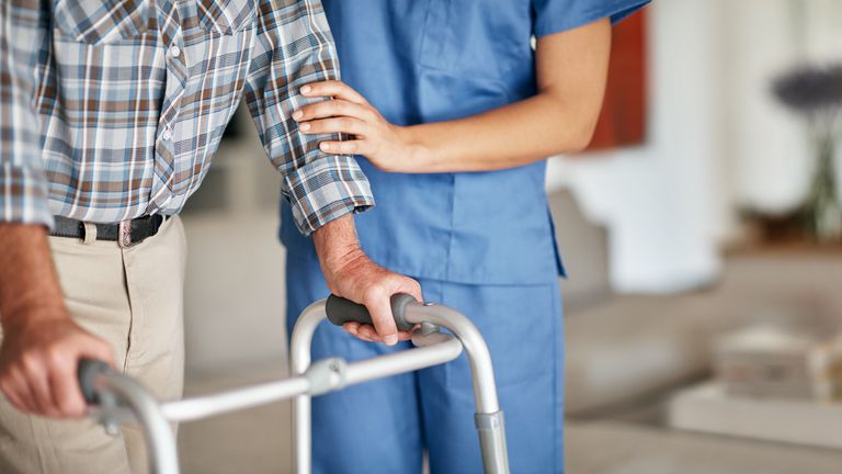 Shot of a woman assisting her elderly patient who&#39;s using a walker for support