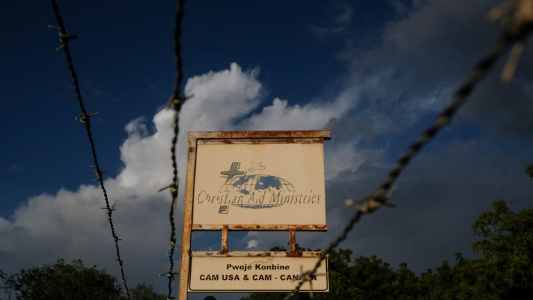 A custom sign stands outside Christian Aid Ministries in Titanyen, Haiti, Thursday, Oct. 21, 2021.  The leader of the 400 Mawozo gang that police say is holding 17 members of the kidnapped Christian Aid Ministries missionary group is seen in a video released Thursday saying he will kill them if he doesn’t get what he’s demanding. (AP Photo/Matias Delacroix)