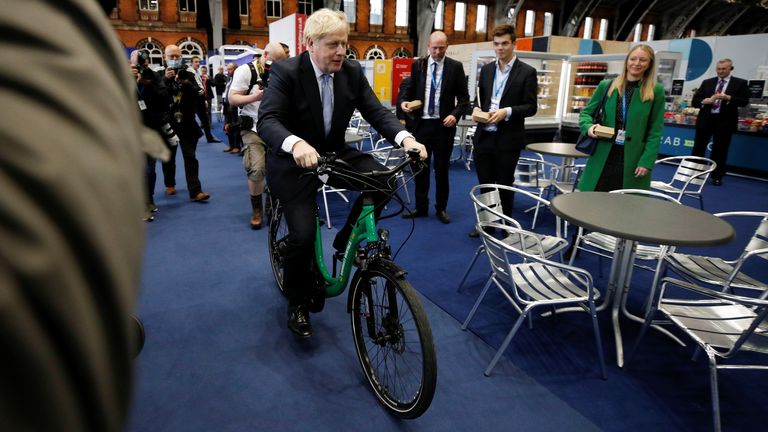 Le Premier ministre britannique Boris Johnson est assis sur un vélo alors qu'il visite un stand commercial à l'intérieur du lieu de la conférence lors de la conférence annuelle du Parti conservateur, à Manchester, en Grande-Bretagne, le 5 octobre 2021. REUTERS/Phil Noble