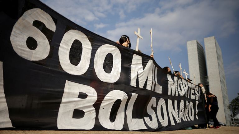 Demonstrators hold a banner and crosses during a protest to pay tribute to Brazil&#39;s 600,000 COVID-19 deaths
