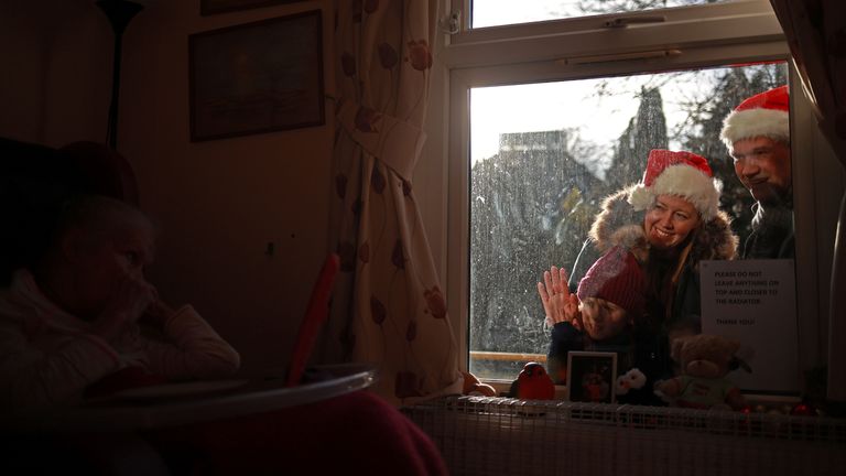 Des proches utilisent un téléphone portable pour parler à un membre de leur famille à travers la fenêtre d'Alexander House Care Home le jour de Noël, alors que la propagation de la maladie à coronavirus (COVID-19) se poursuit à Wimbledon, Londres, Grande-Bretagne, le 25 décembre 2020. Photo prise 25 décembre 2020. REUTERS/Hannah McKay
