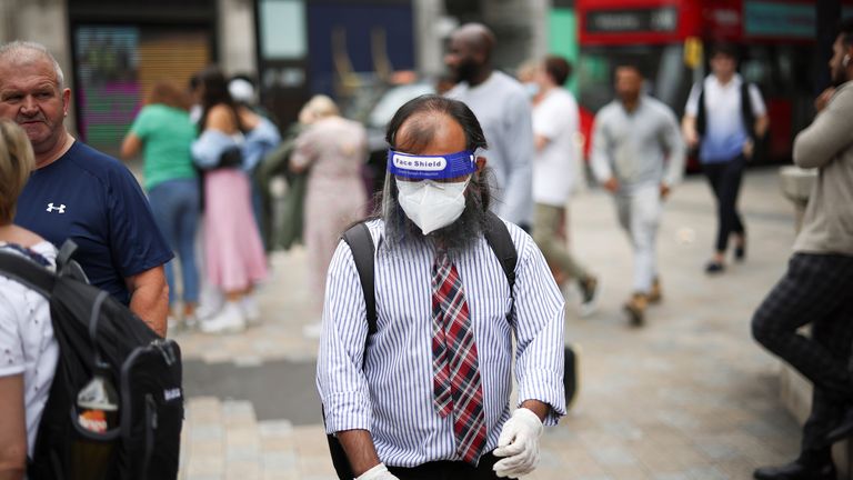 A person wearing a protective face shield and face mask walks through Oxford Circus, amid the coronavirus disease (COVID-19) outbreak, in London
