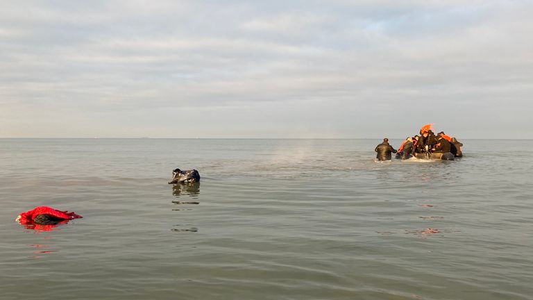 Migrants  - manhandling a large inflatable boat down a northern French beach, to get to the seafront in order to to cross the Channel.  - re copy from  Adam Parsons and Sophie Garratt