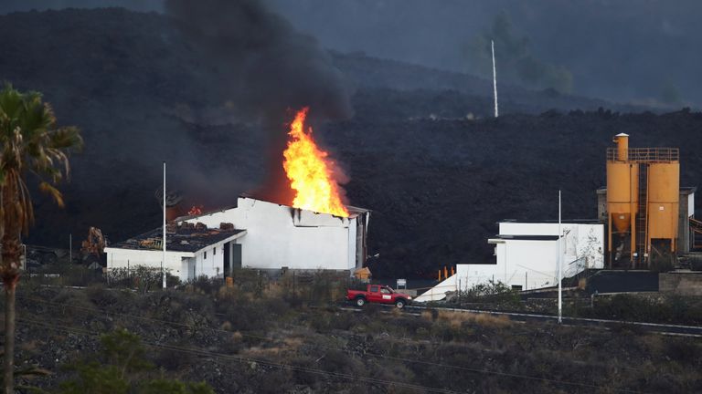 A cement factory in Los Llanos is seen on fire as the Cumbre Vieja volcano continues to erupt on the Canary Island of La Palma, as seen from Tajuya, Spain, October 11, 2021. REUTERS/Sergio Perez
