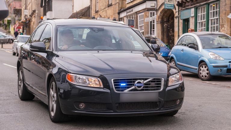 FKKN2J An unmarked police car flashes its blue lights as it speeds through Burford , Oxfordshire , England , Britain , Uk