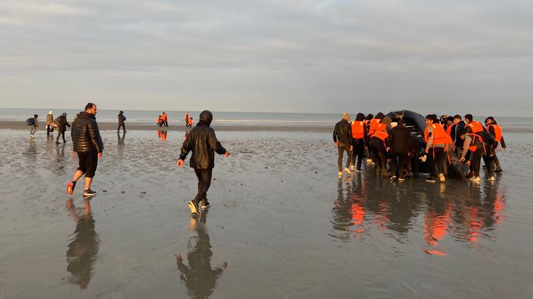 Migrants - malmener un grand bateau pneumatique sur une plage du nord de la France, pour se rendre au bord de mer afin de traverser la Manche.  - recopie d'Adam Parsons et Sophie Garratt