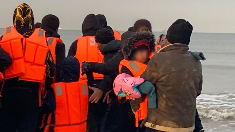 Migrants  - manhandling a large inflatable boat down a northern French beach, to get to the seafront in order to to cross the Channel.  - re copy from  Adam Parsons and Sophie Garratt