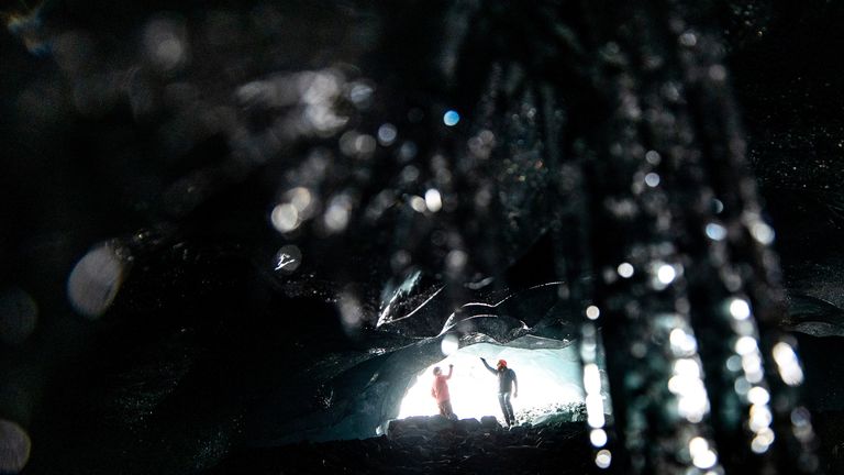 Glaciologists Andrea Fischer and Martin Stocker-Waldhuber, from the Austrian Academy of Sciences, inspect the entrance of a natural glacier cavity of the Jamtalferner glacier near Galtuer, Austria, October 15, 2021. Giant ice caves have appeared in glaciers accelerating the melting process faster than expected as warmer air rushes through the ice mass until it collapses. Picture taken October 15, 2021. REUTERS/Lisi Niesner
