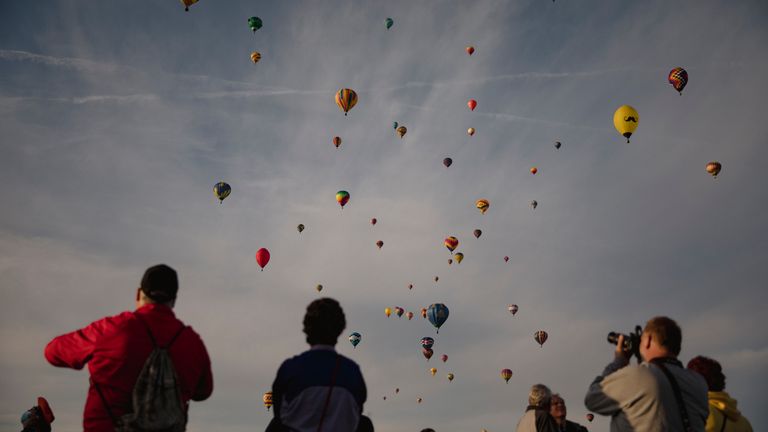 A crowd watches as hundreds of hot air balloons fill the morning sky over Albuquerque, N.M., on the second day of the Balloon Fiesta on Sunday, Oct. 3, 2021.  (Adria Malcolm/The Albuquerque Journal via AP)