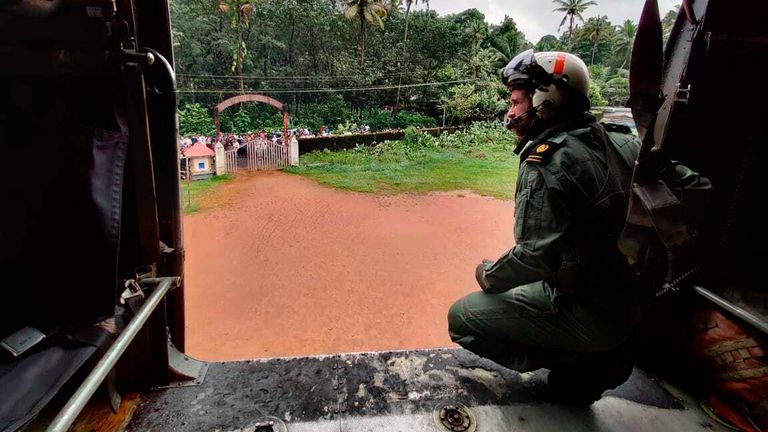 インド海軍によって提供されたこの画像は、ケララ州南部のコッタヤム地区にあるコッタヤム地区のコッタヤムで洪水の影響を受けた人々に救援物資を配布する任務でヘリコプターから外を見ている海兵隊員を示しています。