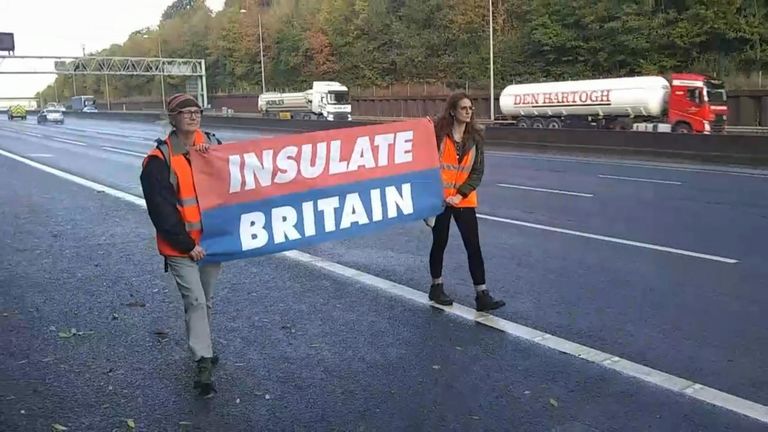 Activistas de Insulate Britain caminan por el arcén de la M25 
