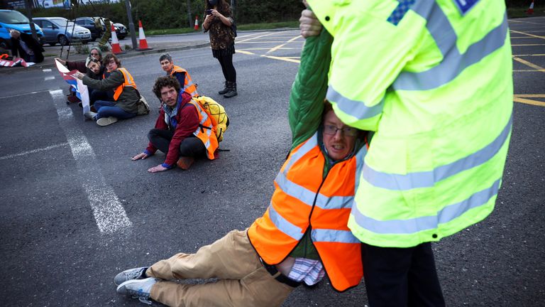 A police officer detains an Insulate Britain activist blocking a roundabout at a junction on the M25 motorway as they a protest in Thurrock, Britain October 13, 2021. REUTERS/Henry Nicholls
