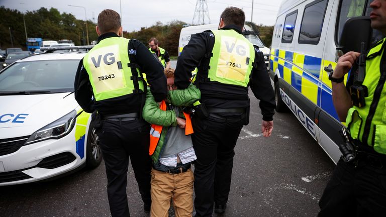 Police officers detain a demonstrator as Insulate Britain activists block a roundabout at a junction on the M25 motorway during a protest in Thurrock, Britain October 13, 2021. REUTERS/Henry Nicholls
